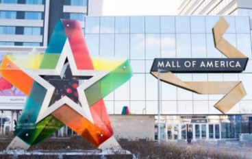 "Mall of America" sign next to a rainbow star with a building in the background