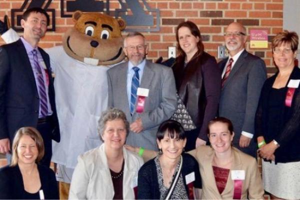 A group of 9 people posed with the UMN mascot Goldy